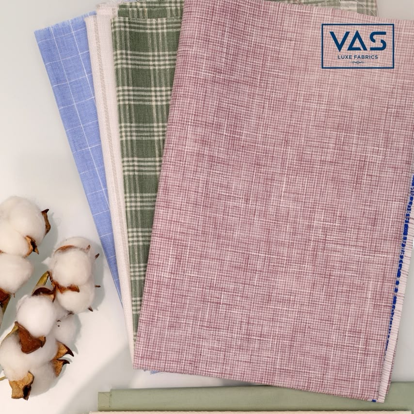 Folded polyester cotton fabrics beside raw cotton bolls