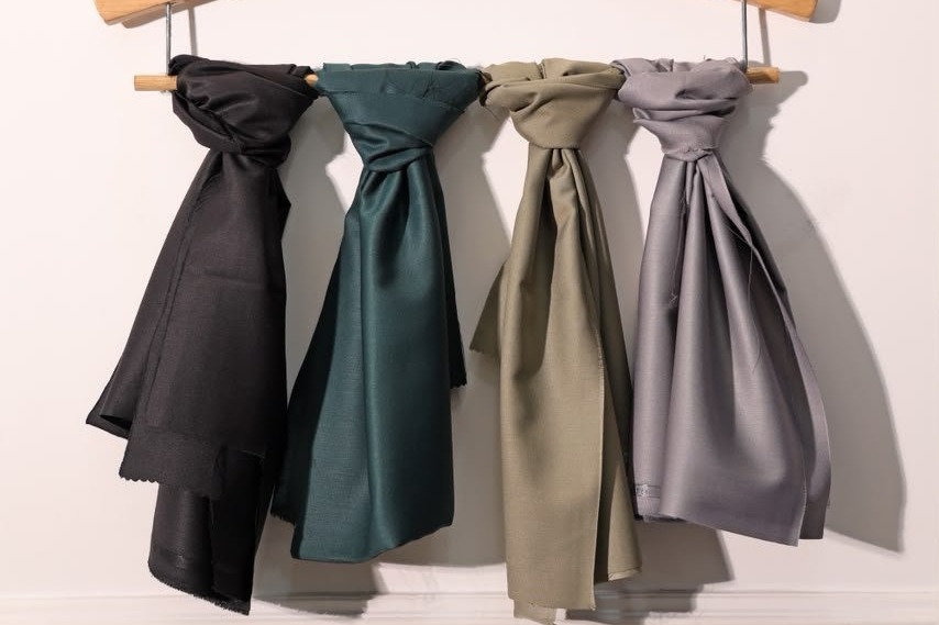 Four VAS scarves knotted on a wooden hanger